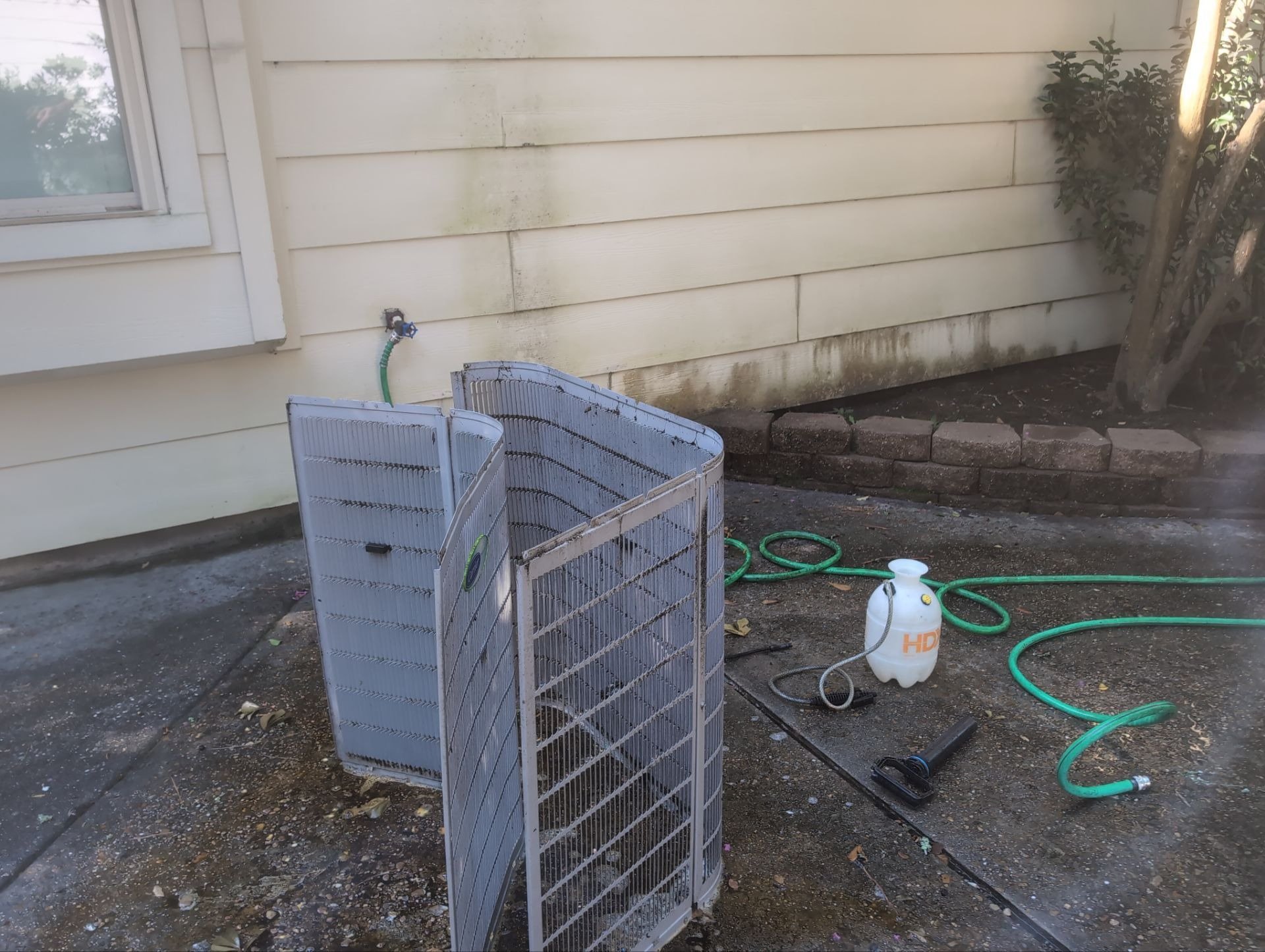 Outdoor AC unit with its outer panels removed for service beside a house