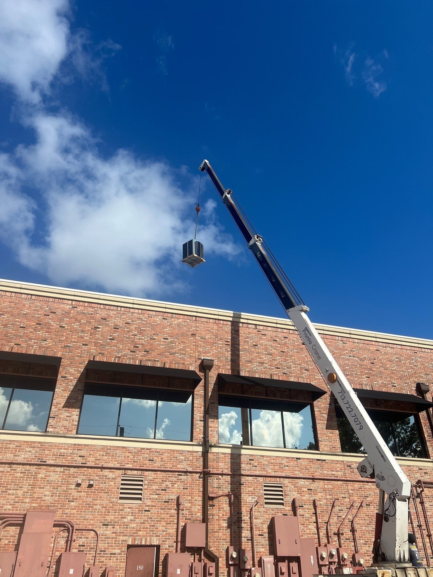Crane setting the new Daikin 7.5-ton unit on the roof